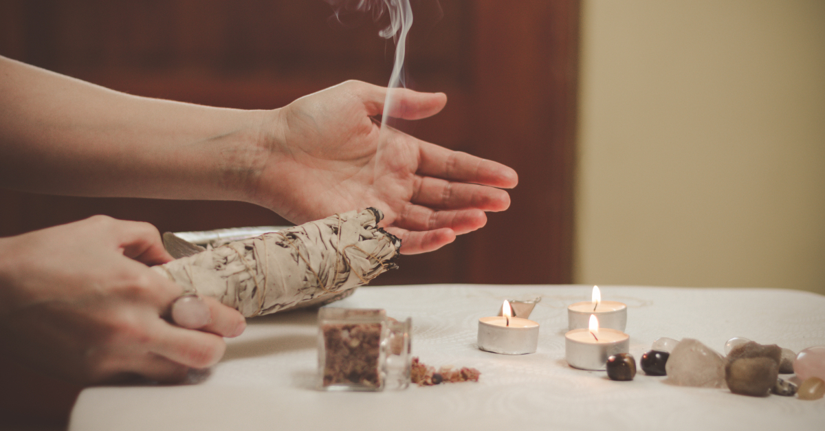 hands burning sage with tealight candles