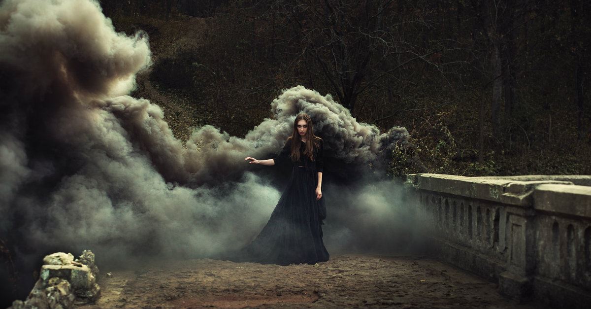 woman wearing black dress in smoke-filled woods